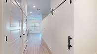 Located at 1301 Lebanon Pike in Nashville, TN, this single-floor unit offers a thoughtfully designed layout comprising a kitchen, living room, and bathroom. The interior is finished with light-toned luxury vinyl plank flooring that runs throughout, complementing the crisp white walls and recessed lighting that keep the space feeling bright and airy.

The kitchen is a standout feature, showcasing a modern two-tone design with warm wood-grain lower cabinets and sleek white upper cabinets. A classic white subway tile backsplash adds texture, while light-colored countertops and a black matte sink faucet provide clean contrast. Stainless steel appliances, including a refrigerator, range, microwave, and dishwasher, complete the functional and stylish setup. Large windows with horizontal blinds allow ample natural light to pour in.

The living area is open and minimalist, with high ceilings that amplify the sense of space. A distinctive black-hardware sliding barn door adds a modern-industrial design element, while a glass door leads to an outdoor balcony area with exterior views.

The bathroom is finished with large-format floor tiles, a wood-toned vanity with a white countertop, and a tub/shower combo featuring vertically laid white tile and matte black fixtures and hardware throughout, tying the space together with a cohesive contemporary aesthetic.