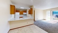 Located at 6010 Creston Ave in Des Moines, Iowa, this 2-bedroom, 1-bathroom unit offers a practical and comfortable single-floor layout. The kitchen is outfitted with warm oak cabinetry, light marble-style countertops, tile flooring, and white appliances including a refrigerator, range, and microwave. A peninsula-style counter opens toward the carpeted living area, creating an open, connected feel between the two spaces.

The bedrooms are carpeted and bathed in natural light from horizontal-blind-covered windows, each equipped with baseboard heating. The primary bedroom is generously sized and includes direct access to a dedicated walk-in closet featuring built-in shelving, dual hanging rods, and ample storage space. The second bedroom also benefits from natural light and a ceiling fan fixture.

The full bathroom features large-format tile flooring, a white vanity with marble-style countertop, a framed mirror, and overhead vanity lighting. Warm-toned wood doors with oak trim carry throughout the unit, contributing to a cohesive aesthetic. Textured ceilings and neutral wall tones provide a clean, move-in-ready backdrop throughout the home.