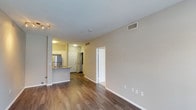 This single-floor unit at 8465 Regents, Unit 146, in San Diego offers a clean, move-in-ready layout with a cohesive and contemporary design throughout. The main living area is finished with rich hardwood-style flooring that extends seamlessly into the adjacent spaces, creating a sense of continuity and warmth. Neutral-toned walls paired with white trim provide a versatile backdrop suited to a variety of interior styles.

The open-concept kitchen is visible from the living area and features a raised breakfast bar with a contrasting gray finish, stainless steel refrigerator, and white cabinetry — offering both functionality and a modern aesthetic. The kitchen is well-lit with overhead lighting, adding brightness to the space.

A hallway connects the living area to the remaining rooms, with interior doors featuring classic paneled designs and bright white finishes. HVAC vents are positioned throughout the ceiling, ensuring efficient climate control across the unit. The layout appears well-organized, with a closet or utility space accessible off the main hallway.

Overall, the unit presents a tidy, practical, and well-maintained living environment with modern finishes, making it a functional and attractive space in the San Diego area.
