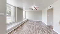 Located in Richardson, TX, this two-story, 2-bedroom, 3-bathroom home offers a well-designed layout spread across two floors. The main level features a bright, open living room with wood-look laminate flooring, a ceiling fan, and large windows that bring in natural light. A built-in bench lines the windowed wall, adding a practical architectural touch. The kitchen is efficiently laid out with white cabinetry, marble-style quartz countertops, a deep double-basin sink, and black appliances including a refrigerator, dishwasher, and range. A convenient pass-through counter connects the kitchen to the adjacent hallway area. One bathroom on the main level is thoughtfully compact, featuring a stacked washer/dryer unit alongside the toilet and vanity, combining laundry and bath functions in one space. Upstairs, the spacious primary bedroom includes a ceiling fan, direct access to an en-suite bathroom with a marble-topped vanity and white cabinetry, and a dedicated walk-in closet with dual hanging rods and wood-look flooring. The second bedroom is well-sized with a ceiling fan and natural light from a window. Throughout the home, consistent wood-look flooring, neutral gray wall tones, and white trim create a clean, cohesive aesthetic.
