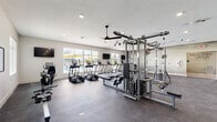 Located at 8710 SW 71st Ave in Ocala, Florida, this single-floor fitness center is a comprehensively outfitted facility designed to support a full range of workout routines. The space is divided into distinct cardio and strength training zones, each thoughtfully arranged to maximize usability and flow.

The cardio area features a lineup of treadmills, ellipticals, stationary bikes, a rowing machine, and a stair climber, all positioned along large windows that offer views of the outdoor pool area with its bright yellow umbrellas — providing natural light and an energizing outlook during workouts. Wall-mounted televisions are positioned throughout for added convenience.

The strength training zone is equally well-appointed, housing a multi-station cable machine, a power rack, free weight benches, barbells, dumbbells, and a variety of resistance machines. Full-length mirrors line the walls to assist with form and technique.

Overhead, ceiling fans provide consistent air circulation throughout the facility, complementing the recessed lighting that keeps the space bright and inviting. The rubberized flooring throughout offers durability and safety underfoot.

A standout design feature is the bold motivational typography wall art, which adds an energetic, modern aesthetic to the training environment. The neutral color palette, clean lines, and open layout create a professional yet welcoming atmosphere well-suited for all fitness levels.
