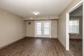 Located at 610 E Scenic Valley Ave in Indianola, Iowa, this single-floor, 2-bedroom, 2-bathroom unit offers a functional and well-appointed layout. The open-concept kitchen and living area serves as the heart of the home, featuring warm hardwood-style flooring throughout. The kitchen is equipped with rich cherry wood cabinetry, granite-style countertops, a dishwasher, electric range, and a range hood, providing generous counter and storage space. The living area benefits from natural light streaming through a set of French doors that open to the exterior. Both bedrooms are carpeted for comfort and each includes closet space — four closets total throughout the unit, offering abundant storage. The primary bedroom is a comfortable size with its own dedicated closet. The two bathrooms are finished with hardwood-style flooring, cherry wood vanities, and white fixtures; one bathroom features a full tub-shower combination. A dedicated laundry area adds everyday convenience. Neutral, warm-toned walls throughout create a clean and welcoming ambiance, while white six-panel interior doors and crisp trim provide a cohesive, polished look across the entire unit.