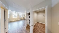 Located at 272 E Main St in the heart of downtown Rochester, NY, this one-bedroom, one-bathroom unit offers a thoughtfully designed single-floor layout with modern finishes throughout. The open-concept living and kitchen area is bright and inviting, featuring wide-plank hardwood-style flooring, tall windows with urban views, and track lighting that illuminates the space efficiently. The kitchen is well-appointed with light wood cabinetry, a white tile backsplash, stainless steel appliances including a gas range, dishwasher, and refrigerator, as well as an over-the-range microwave. The layout flows seamlessly through connecting hallways, lending the space a clean, organized feel. The spacious primary bedroom is carpeted for comfort, features a large window that brings in natural light, and includes a double-door closet offering generous storage. The bathroom is finished with a walk-in tile shower boasting large-format white subway tiles, a neutral accent band, mosaic tile flooring, a sliding glass door, and a contemporary wood-toned vanity with a white countertop. Neutral tones throughout create a calm, cohesive ambiance suited for modern urban living.