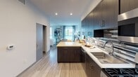 Located on West Pico Boulevard in Los Angeles, this contemporary single-floor residence offers a thoughtfully designed open layout with modern finishes throughout. The kitchen is a standout feature, showcasing dark espresso cabinetry that extends to the ceiling, a mosaic tile backsplash, stainless steel appliances, and a light quartz peninsula with seating for casual dining. Wood-look plank flooring flows seamlessly throughout the space, connecting each area with a cohesive aesthetic. The open living area benefits from natural light through large windows and transitions naturally into the sleeping area, which is elegantly defined by a black metal open-shelf unit. The bedroom is well-appointed with a walk-in closet accessible through a modern barn-style frosted glass sliding door, complemented by a secondary closet nearby. The bathroom features clean white walls, tile flooring, a generous vanity, and a shower with a curtain enclosure. Recessed lighting throughout provides a warm, layered ambiance. The overall design blends coastal-inspired décor with clean, urban modern sensibilities, creating a functional and visually cohesive living environment well-suited to the West Los Angeles lifestyle.