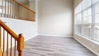 Located at 10090 Mill Run Cir in Owings Mills, MD, this multi-level home spans four floors and offers a well-organized layout with 3 bedrooms, 2 bathrooms, and an attached garage. The entry-level garage is spacious, equipped with an automatic opener, and includes built-in storage with double arched doors leading directly into the home. The main living level features warm hardwood-style flooring, soaring ceilings, and large windows that flood the space with natural light. A classic fireplace serves as a focal point in the living area, complemented by a staircase with a handsome wood banister. The kitchen is well-appointed with white cabinetry, dark granite countertops, white appliances, and a window above the sink overlooking greenery. An adjacent dining or flex room provides additional living space. Upper floors are home to the three bedrooms, including a generously sized primary bedroom with plush carpeting, vaulted ceilings, and a large window offering outdoor views. The primary suite includes direct access to a full bathroom featuring a tiled tub-shower combo and white vanity. A second full bathroom with wood-look tile flooring serves the remaining bedrooms. Throughout, the home maintains a neutral, warm palette with clean white trim, creating a bright and welcoming ambiance.