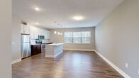 Located at 6770 Printers Blvd in New Albany, Ohio, this one-bedroom, one-bathroom residence offers a well-designed single-floor layout that maximizes both function and comfort. The heart of the unit is an open-concept kitchen and living area, where rich hardwood-style flooring flows throughout. The kitchen is outfitted with stainless steel appliances—including a refrigerator, electric range, and microwave—complemented by crisp white upper cabinetry, dark lower cabinetry, and a central island with a white countertop and undermount sink. Stylish pendant lighting hangs above the island, adding a modern touch. Large windows along the living area allow natural light to fill the space, creating a bright and inviting atmosphere. A dedicated entrance leads into the unit, offering a clean transition into the main living space. The generously sized primary bedroom features plush carpeting, two windows with outdoor views, and ample room for furniture arrangement. The bathroom includes a white vanity with a clean countertop, a large mirror, and contemporary lighting fixtures, with hardwood-style flooring continuing the cohesive aesthetic. A closet provides additional storage, rounding out this thoughtfully designed and move-in-ready residence.