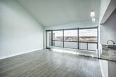 This 2-bedroom, 1-bathroom residence in Memphis, TN offers a thoughtfully designed single-floor layout combining modern finishes with an open, airy atmosphere. The living area is a standout, boasting soaring ceilings, light hardwood-style flooring, and a dramatic wall of floor-to-ceiling windows that frame sweeping city views and flood the space with natural light. A ceiling fan adds both function and style overhead.

The open kitchen flows seamlessly into the living space and features granite countertops, a peninsula with a built-in sink, rich wood-toned cabinetry, and a full suite of stainless steel appliances including a gas range, microwave, and refrigerator. Pendant lighting accents the peninsula area.

Both bedrooms are generously proportioned with light hardwood-style flooring and ceiling fans. The primary bedroom features notably high ceilings with clerestory windows, while the secondary bedroom includes a city-facing window with urban views.

The bathroom is finished with large-format dark tile flooring, floor-to-ceiling tiled walls in the shower/tub combination, a granite-topped vanity, and modern fixtures. The overall aesthetic throughout is clean and contemporary, with a neutral color palette of whites and soft grays creating a cohesive, move-in-ready environment.