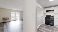 Located at 151 Sea St in Quincy, MA, this one-bedroom, one-bathroom unit offers a thoughtfully designed single-floor layout that maximizes every square foot. The open-concept living area is bright and airy, featuring light-toned luxury vinyl plank flooring that runs throughout the entire unit, neutral wall tones, and a textured ceiling. Sliding glass doors lead directly to a private balcony, filling the living room with natural light and offering outdoor views. A wall-mounted A/C unit and baseboard heating provide year-round comfort. The kitchen is efficiently laid out with crisp white cabinetry, open shelving, light countertops, and black appliances including an electric range and dishwasher. A pass-through opening connects the kitchen to the living area, enhancing the open feel of the space. The bedroom is generously proportioned, offering a large double-door closet, a dedicated window for natural light, and the same consistent flooring found throughout the unit. The full bathroom includes a tub/shower combo, a white vanity with sink, and coordinating vinyl flooring. Clean, modern finishes and a cohesive neutral palette give this unit a move-in-ready appeal.
