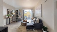 Located at 6430 Verner Ave in Sacramento, California, this well-appointed single-story residence offers a thoughtfully designed layout with a warm, contemporary aesthetic throughout. The living room serves as a welcoming centerpiece, featuring wood-style flooring, a built-in shelving nook, and a sliding glass door that opens to a private balcony, allowing natural light to pour in and providing a seamless indoor-outdoor connection. The kitchen is efficiently arranged with crisp white cabinetry, stainless steel appliances including a refrigerator, electric range, and microwave, and is conveniently adjacent to a dining area with mirrored closet doors that visually expand the space. The dining area also reveals an in-unit laundry closet, adding everyday convenience. The primary bedroom is carpeted and generously sized, offering direct access to a walk-in closet and a private en-suite bathroom with white vanity cabinetry, a large mirror, and a tub-shower combination. A second bedroom provides comfortable accommodations with a window and closet. The second full bathroom mirrors the same clean, bright design as the primary bath. Neutral tones and consistent finishes tie the entire residence together, creating a cohesive and functional living environment.