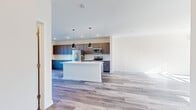 Located at 230 Stoneycrest Dr in Middletown, CT, this contemporary multi-floor home offers 2 bedrooms, 3 bathrooms, and a thoughtfully designed layout spread across three levels. Light-toned hardwood-style flooring flows consistently throughout, creating a cohesive and modern aesthetic.

The main level is anchored by a spacious open-concept kitchen and living area. The kitchen is a standout feature, showcasing two-tone cabinetry — deep blue lower cabinets paired with dark taupe uppers — complemented by a classic white subway tile backsplash, light quartz countertops, stainless steel appliances including a refrigerator, range, and microwave, and a central island perfect for dining or entertaining. The adjacent living area is bright and airy, with multiple windows inviting generous natural light.

The upper level houses the bedrooms, including a well-proportioned primary suite with a dedicated walk-in closet outfitted with a custom shelving and hanging system. Each bathroom features gray cabinetry, white countertops, brushed nickel fixtures, and wood-look flooring, maintaining the home's clean, modern character. One bathroom includes a tiled tub/shower combo.

A wall-mounted mini-split system provides efficient climate control, while recessed lighting throughout adds to the home's polished, move-in-ready appeal.