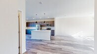 Located at 230 Stoneycrest Dr in Middletown, CT, this contemporary multi-floor home offers 2 bedrooms, 3 bathrooms, and a thoughtfully designed layout spread across three levels. Light-toned hardwood-style flooring flows consistently throughout, creating a cohesive and modern aesthetic.

The main level is anchored by a spacious open-concept kitchen and living area. The kitchen is a standout feature, showcasing two-tone cabinetry — deep blue lower cabinets paired with dark taupe uppers — complemented by a classic white subway tile backsplash, light quartz countertops, stainless steel appliances including a refrigerator, range, and microwave, and a central island perfect for dining or entertaining. The adjacent living area is bright and airy, with multiple windows inviting generous natural light.

The upper level houses the bedrooms, including a well-proportioned primary suite with a dedicated walk-in closet outfitted with a custom shelving and hanging system. Each bathroom features gray cabinetry, white countertops, brushed nickel fixtures, and wood-look flooring, maintaining the home's clean, modern character. One bathroom includes a tiled tub/shower combo.

A wall-mounted mini-split system provides efficient climate control, while recessed lighting throughout adds to the home's polished, move-in-ready appeal.