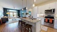 Located at 3000 Fast Ln in Fort Mill, SC, this single-floor residence offers a thoughtfully designed open-concept layout with contemporary finishes throughout. The kitchen serves as a central hub, featuring crisp white cabinetry, granite countertops, stainless steel appliances including a range, microwave, and French door refrigerator, and a large center island with pendant lighting and bar seating — ideal for both cooking and casual dining. Warm wood-look flooring flows seamlessly into the living area, which is anchored by a bold teal accent wall, a ceiling fan, and French doors that open to a private balcony, filling the space with natural light and outdoor views. The two bedrooms each feature distinct accent walls — one in deep green, one in warm terracotta — creating inviting, personality-rich retreats with plush carpet flooring. The primary bathroom includes a walk-in tiled shower, while a second bathroom offers a full tub-shower combo with classic white subway tile. A walk-in closet with built-in shelving provides ample storage. Throughout the residence, the design balances modern aesthetics with warm, earthy tones, resulting in a comfortable and cohesive living environment.