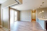 Located at 17607 East 61st Avenue in Denver, CO, this one-bedroom, one-bathroom residence offers a well-designed single-floor layout with a thoughtful blend of modern finishes and functional living spaces. The open-concept main area seamlessly combines the living room, dining area, and kitchen, all finished with light wood-look flooring that enhances the bright, airy feel of the space. The kitchen is a standout feature, boasting rich walnut-toned cabinetry, crisp white countertops, stainless steel appliances including a refrigerator, range, and built-in microwave, and a peninsula island with pendant lighting overhead — ideal for both cooking and casual dining. A sliding glass door leads from the living area to a private balcony offering open, scenic views of the surrounding landscape. The bedroom is a comfortable retreat, carpeted for warmth, with a ceiling fan, ample natural light from dual windows, and generous closet space. The bathroom is finished with clean, white tile, a soaking tub/shower combo, and a sleek vanity featuring walnut cabinetry and white countertops. Additional conveniences include in-unit laundry, a utility room, hallway storage, and multiple closets throughout.