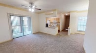This single-floor, two-bedroom, two-bathroom unit offers a spacious and functional layout designed for comfortable everyday living. The open-concept living and dining area is anchored by plush carpeting and a ceiling fan with integrated lighting. A sliding glass door dressed with vertical blinds fills the space with natural light and provides access to an outdoor area. Adjacent to the living space, a dedicated dining area features crown molding details and a pendant light fixture.

The galley-style kitchen is well-equipped with light wood cabinetry, a double-basin sink, a full suite of white appliances including a dishwasher, range, microwave, and refrigerator, and hard surface flooring throughout. A breakfast bar connects the kitchen to the living area.

Both bedrooms are generously sized, finished with soft carpet, and feature windows with blinds that allow natural light to filter in. One bedroom includes a ceiling fan, while the other offers ample wall space for flexible furniture arrangement.

The two bathrooms each include a soaking tub with tiled surround, a toilet, and vanity with light wood cabinetry. One bathroom features an extended double-sink vanity with a large mirror, while both share the same warm wood-look flooring.