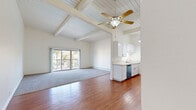Located at 23825 Anza Ave in Torrance, CA, this 2-bedroom, 3-bathroom residence offers a thoughtfully designed layout across a single floor. The open-concept living and dining area immediately impresses with its vaulted, wood-planked ceilings accented by exposed beams and a ceiling fan, creating an airy, spacious ambiance. Warm hardwood flooring flows through the main living areas, while plush carpeting defines the living room zone and bedrooms. Sliding glass doors flood the space with natural light and open to a private balcony with outdoor views. The galley-style kitchen is well-appointed with white shaker cabinetry, light stone countertops, stainless steel appliances including a range and built-in microwave, a dishwasher, and a decorative pendant chandelier overhead. The bathrooms feature clean white cabinetry, marble-style stone countertops, framed mirrors, and tub/shower combinations. The bedrooms are generously sized with carpeted floors, beamed ceilings, large windows for natural light, and mirrored sliding closet doors with gold-tone frames. An interior staircase adds architectural interest to the living area. Baseboard heating is present throughout, ensuring year-round comfort in this bright, well-maintained Torrance residence.