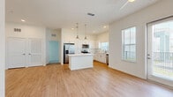 This single-story home offers a thoughtfully designed layout across 3 bedrooms, 2 bathrooms, and a combined kitchen and living area. The open-concept kitchen and living space serves as the heart of the home, showcasing light wood-style flooring, white shaker cabinetry, stone countertops, and a central island with pendant lighting overhead. Stainless steel appliances — including a refrigerator with ice dispenser, range, and microwave — complete the modern kitchen. Natural light streams through multiple windows, enhancing the bright, airy atmosphere. The living area features a ceiling fan and a glass door that opens to the exterior, bringing in additional light and outdoor views. The bedrooms are carpeted and finished in neutral tones, with windows providing natural light and neighborhood views. The primary bedroom includes double closet doors and access to a spacious walk-in closet with wire shelving systems. Both bathrooms feature tiled tub-shower combinations with clean white finishes and wood-style flooring. One bathroom includes a window above the shower for added natural light. Throughout the home, the consistent use of light colors, clean lines, and functional design creates a cohesive and inviting living environment.
