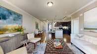 Located at 5565 Mansions Bluffs in San Antonio, TX, this single-story, 2-bedroom, 2-bathroom home offers a thoughtfully designed open-concept layout finished with rich hardwood flooring and elegant crown molding throughout. The living room is generously proportioned, filled with natural light from large windows framed by floor-length drapes, and flows seamlessly into the dining area and kitchen. The kitchen features dark espresso cabinetry, granite countertops, black appliances, track lighting, and a peninsula with bar seating — ideal for casual dining and entertaining. A hallway with arched architectural detailing connects the living spaces to the private quarters. The spacious primary bedroom includes crown molding, hardwood floors, and direct access to a walk-in closet with built-in shelving and hanging rods. The primary bathroom offers a dual-sink vanity with dark cabinetry and granite counters, a soaking tub with tile surround, and a separate glass-enclosed shower. The second bedroom is cozy and well-sized with its own closet. Additional spaces include a dedicated laundry room, pantry, patio, and an attached garage, rounding out this complete and functional home.