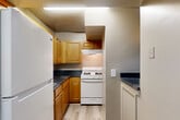 Located at 820 Southern Ave SE in Washington, DC, this single-floor residence offers three bedrooms, two bathrooms, and a practical layout designed for comfortable living. The combined dining and living area provides an open, flexible space finished with light-toned laminate flooring and neutral gray walls, allowing natural light to flow in through a large window overlooking the outdoors. A hallway connects the main living areas to the private quarters, with four closets distributed throughout for ample storage. The kitchen is efficiently arranged in an L-shaped configuration, featuring warm honey-toned wood cabinetry, dark granite-style countertops, a gas range, and a full-size refrigerator, all set above light wood-look flooring. The three bedrooms are finished with plush gray carpeting and neutral walls, each receiving natural light through windows with blinds. The primary bedroom offers a comfortable footprint with direct access to the rest of the unit. The bathrooms include a tub-shower combination with clean white tile surrounds. Textured ceilings are present throughout the unit, adding a classic residential character to the overall aesthetic.