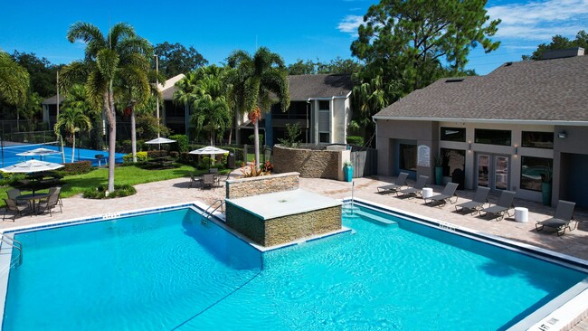 Relájese con estilo en la piscina Harper Grand, que cuenta con exuberantes palmeras, cómodos sillones y una fuente de agua serena para una máxima relajación. - Harper Grand