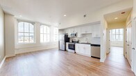 Located at 9 Garfield Pl in Cincinnati's vibrant urban core, this 2-bedroom, 2-bathroom residence offers a thoughtfully designed, single-floor layout. The open-concept kitchen and living area serves as the heart of the home, featuring warm light wood-style flooring throughout, recessed lighting, and generous natural light from large, tall windows that frame views of the Cincinnati skyline. The kitchen is outfitted with white shaker-style cabinetry, dark countertops, a marble-style tile backsplash, and a full suite of stainless steel appliances including a refrigerator, electric range, microwave, and dishwasher. The spacious primary bedroom offers ample room and includes a closet, while the second bedroom is equally well-lit with a large city-facing window. Both bedrooms continue the light flooring aesthetic with neutral wall tones. The two bathrooms are finished with clean, modern fixtures; one features a tiled tub-shower combo with a curved glass rod and a distinctive geometric-patterned tile floor with dark granite vanity counters. With five closets distributed throughout, storage is a notable strength. The unit's layout connects rooms through a central hallway, providing a practical and well-organized flow.