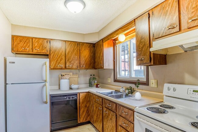 Kitchen wood cabinets white appliances large window - Highland Apartments