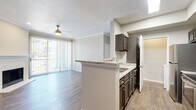 This thoughtfully designed single-story home offers a comfortable and functional layout across one floor. The open-concept living and kitchen area serves as the heart of the home, featuring wood-style flooring, crown molding, and a ceiling fan that adds to the welcoming ambiance. A sliding glass door floods the living room with natural light and provides access to the outdoors, while a classic white-mantled fireplace anchors the space with warmth and character. Built-in shelving adds a practical and decorative touch near the living area.

The kitchen is well-equipped with dark cabinetry, granite countertops, stainless steel appliances, and a peninsula that doubles as a breakfast bar — seamlessly connecting the cooking and living spaces. A skylight above enhances the kitchen's bright, airy feel.

The bedroom is generously sized, carpeted for comfort, and includes a ceiling fan, a window with natural light, and built-in shelving for additional storage. A dedicated closet provides ample organization space.

The bathroom is clean and modern, featuring a granite-topped vanity with dark cabinetry, a full tub/shower combination, and wood-style flooring. Completing this home is a dedicated in-unit laundry room with side-by-side washer and dryer hookups and additional shelving above.