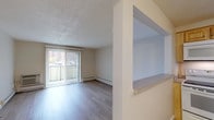 Located at 49 Highland Ave in Randolph, Massachusetts, this single-floor unit offers a well-organized layout with distinct living, dining, kitchen, bedroom, and bathroom areas. The living room is a bright, open space featuring light wood-style flooring, a textured ceiling, and a sliding glass door flanked by vertical blinds that opens to a private balcony with outdoor views. Baseboard heating runs along the perimeter, and a wall-mounted HVAC unit provides additional climate control. A pass-through window with a countertop connects the living/dining area to the kitchen, creating an open and communicative feel between spaces. The kitchen is equipped with warm wood cabinetry, laminate countertops, a stainless steel sink, a dishwasher, and a refrigerator, offering ample storage and functionality. The dining area, adjacent to the kitchen, continues the light wood flooring and features a pass-through that enhances the open layout. The bedrooms are carpeted in a neutral gray tone and include louvered bifold closet doors, windows with natural light, and baseboard heating. The bathroom features a full tub and shower combo with white subway tile surround, a grab bar, a single-sink vanity with white cabinetry, and a mirrored medicine cabinet above.