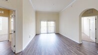 This single-floor, 2-bedroom, 2-bathroom home offers a thoughtfully designed layout that maximizes functionality and comfort. The living room features rich, dark hardwood-style flooring, crown molding, and a sliding glass door that invites natural light and provides outdoor access, creating an open and airy atmosphere.

The kitchen is well-equipped with light wood cabinetry, a subway tile backsplash, a peninsula with a built-in sink and white countertops, and black appliances including a refrigerator with ice maker, electric range, and microwave. Light tile flooring completes this practical and attractive space.

Both bedrooms are carpeted and generously sized, with the primary bedroom featuring multiple windows fitted with horizontal blinds that allow for ample natural light. A walk-in closet with built-in shelving and rod systems is accessible directly from the primary bathroom, which includes a warm wood-toned vanity with white countertops and tile flooring.

The second bedroom also features plush carpet and windows with blinds. A dedicated in-unit laundry room accommodates a full-sized washer and dryer alongside a storage shelf. Two hallways connect the space efficiently. Throughout, the home maintains a clean, neutral palette with cream-toned walls and white trim.