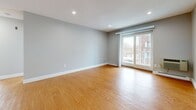 Located at 151 Sea St in Quincy, MA, this two-bedroom, one-bathroom residence offers a functional and well-appointed single-floor layout. Warm hardwood flooring flows consistently throughout the living areas and bedrooms, lending a cohesive and inviting feel to the space.

The combined kitchen and living room area provides an open, practical layout. The kitchen features warm-toned wood cabinetry with granite-style countertops, black appliances including a range, dishwasher, and refrigerator, and light vinyl plank flooring. The living room is bright and airy, benefiting from recessed lighting and sliding glass doors that open to a private balcony with outdoor views.

The primary bedroom is generously sized, featuring two large windows that fill the room with natural light, recessed lighting, and baseboard heating. The second bedroom also offers good proportions, complete with a built-in louvered closet and a large window. Both bedrooms are finished in the same neutral gray palette with clean white trim.

The bathroom is a standout feature, showcasing elegant marble-style tile surround in the tub and shower area, paired with a white vanity and wood-look flooring, creating a clean and refined aesthetic.

Throughout the space, neutral gray walls, white baseboards, and recessed lighting provide a modern, move-in-ready atmosphere.