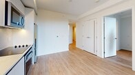 Located at 707 Terry Ave North in Seattle's First Hill neighborhood, this one-bedroom, one-bathroom unit offers a thoughtfully designed layout across a single floor. Light wood flooring flows throughout, lending the space a clean, contemporary feel complemented by crisp white walls and recessed lighting.

The kitchen is outfitted with flat-front cabinetry, stainless steel appliances including a refrigerator, oven, and microwave, and a tile backsplash — all arranged in an efficient galley-style configuration open to the main living area. The living space benefits from a glass door that opens onto a private balcony, offering elevated views of the surrounding Seattle cityscape.

The bedroom provides a comfortable retreat with warm wood flooring and direct access to a walk-in closet. A second closet adds additional storage elsewhere in the unit. In-unit laundry further enhances everyday convenience.

The bathroom features a soaking tub with an overhead shower, a clean white vanity, and speckled tile flooring, maintaining the unit's modern and minimalist aesthetic throughout. A hallway connects the spaces efficiently, keeping the layout organized and functional. The balcony features an industrial-style perforated metal railing and exposed concrete accents, reflecting the building's modern urban character.