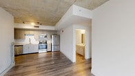 Located on the 8th floor in the heart of Miami's Brickell neighborhood, this 2-bedroom, 2-bathroom unit offers a modern urban living experience with distinctive industrial-inspired design elements. The open layout connects the kitchen and living areas seamlessly, all unified by durable wood-style flooring throughout.

The kitchen is well-appointed with light gray cabinetry, white quartz countertops, a deep undermount sink with a sleek industrial-style faucet, and a full suite of stainless steel appliances including a French door refrigerator, electric range, and built-in microwave. A striking exposed concrete ceiling adds an industrial character to the main living area, complemented by recessed track lighting.

The primary bedroom is generously sized and features floor-to-ceiling windows that frame views of the Miami skyline and surrounding palm-lined streets, allowing for abundant natural light. The second bedroom also benefits from the exposed concrete ceiling aesthetic and direct access to the main living space.

Both bathrooms are finished with wood-look tile flooring, neutral stone-tiled tub-shower combinations, white vanities with undermount sinks, and clean white walls. A dedicated closet provides additional storage. The overall ambiance is clean, contemporary, and well-suited to the vibrant Miami urban lifestyle.