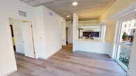 Located in Chicago's vibrant Old Town neighborhood along N Sedgwick Street, this single-floor unit showcases a clean, modern design aesthetic throughout. A defining architectural feature is the exposed concrete ceiling, which lends an industrial character that contrasts beautifully with the warm, light-toned hardwood flooring found throughout the living spaces.

The open-concept layout connects the living area to a well-appointed kitchen. The kitchen features white flat-panel cabinetry, stainless steel appliances including a gas range and French door refrigerator, a dark tile backsplash, and a sleek peninsula with a white countertop and undermount stainless steel sink — ideal for both cooking and casual dining. A linear pendant light fixture above the peninsula adds a contemporary touch.

The living area is flooded with natural light through large floor-to-ceiling windows that offer direct views of the surrounding streetscape and tree-lined neighborhood. The bedroom also benefits from exterior window access, maintaining the unit's bright and airy feel. A hallway connects the private spaces, including a bathroom finished with large-format dark tile flooring, a white floating vanity with an illuminated mirror, and clean, minimalist fixtures. The overall ambiance is modern, light-filled, and thoughtfully designed for urban living.