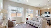 Located in Broken Arrow, Oklahoma, this single-story home showcases a thoughtfully designed open-concept layout finished with modern, neutral tones and light wood-look flooring that flows consistently throughout. The living area is generously sized, bathed in natural light from multiple large windows dressed with white sheer curtains and horizontal blinds. A ceiling fan overhead and access to an adjacent outdoor area enhance the room's comfort and functionality.

The kitchen serves as a central hub of the home, featuring light wood-grain cabinetry extending floor to ceiling for ample storage, granite-look countertops, and a suite of stainless steel appliances including a refrigerator, range, and built-in microwave. A kitchen island with bar seating and pendant globe lighting above adds both workspace and a casual dining option.

The bedroom is bright and serene, with a well-sized window allowing natural light to filter in, complemented by clean white walls and warm flooring. The bathroom is efficiently designed with wood-tone cabinetry, a granite-topped vanity, wood-look flooring, and a small window for natural ventilation. The overall ambiance throughout the home is clean, contemporary, and inviting.