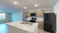 Located at 4311 Shoppers Lane in Columbus, Ohio, this single-floor, 2-bedroom, 1-bathroom residence offers a well-designed layout with consistent wood-look flooring and neutral gray tones throughout. The open-concept kitchen and living area serves as the heart of the home, featuring a central island with a granite countertop and built-in sink, warm taupe cabinetry with matching granite surfaces, and a full suite of black Whirlpool appliances including a refrigerator, range, and over-the-range microwave. Both bedrooms are generously proportioned, each outfitted with ceiling fans, ample natural light from double windows with blinds, and access to outdoor views. The primary bedroom includes a spacious walk-in closet with wire shelving systems providing extensive storage. The bathroom continues the clean, modern aesthetic with wood-look flooring and chrome fixtures. Throughout the home, crisp white trim, recessed lighting, and neutral wall tones contribute to a bright and functional ambiance. A dedicated utility area with an electrical panel adds practical convenience to this thoughtfully arranged single-story residence.