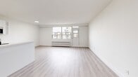 Located at 79 Jameson Avenue in Toronto's vibrant Parkdale neighbourhood, this thoughtfully renovated one-bedroom, one-bathroom unit offers a clean, modern aesthetic throughout. The open-concept kitchen and living area form the heart of the space, featuring light-toned laminate flooring, crisp white walls, and recessed lighting. The kitchen is well-appointed with sleek white cabinetry, quartz countertops, a deep undermount sink, and a full suite of stainless steel appliances including a refrigerator, electric range, and over-the-range microwave. A generous living area extends from the kitchen, bathed in natural light from large windows that frame views of the surrounding neighbourhood. The bedroom is a comfortable retreat with its own large window and sliding closet, continuing the light, neutral palette. The bathroom is elegantly finished with a white vanity topped in quartz, a combined tub and shower enclosure clad in striking marble-effect tile, and gold-accented hardware that adds a refined touch. Radiator heating is present throughout, and a dedicated hallway with a closet provides practical storage. The overall ambiance is bright, clean, and move-in ready.