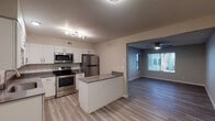 This single-floor residence offers a thoughtfully designed layout that balances modern aesthetics with everyday functionality. The open-concept kitchen is a standout feature, outfitted with crisp white shaker-style cabinetry, gray quartz-style countertops, a classic subway tile backsplash, and a full suite of stainless steel appliances including a range, built-in microwave, and refrigerator. A kitchen island with a matching countertop provides additional prep space and serves as a natural transition into the adjoining living area. Track lighting over the kitchen and a ceiling fan in the living space ensure both areas are well-lit and comfortable.

Throughout the residence, light-toned wood-look flooring adds warmth and continuity, complemented by neutral gray walls and clean white baseboards. The bedrooms are generously proportioned, each featuring a ceiling fan with integrated lighting, blinds-covered windows that allow for natural light, and textured ceilings. The bathroom includes a full tub and shower combination with white tile surround and a modern brushed nickel rain showerhead. The overall ambiance is clean, contemporary, and move-in ready, with a cohesive design language that carries throughout every room.