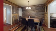 Located at 301 Castlewood Dr in New Braunfels, TX, this single-floor unit blends rustic charm with practical design throughout its well-organized layout. The dining area is a standout, enveloped in reclaimed barnwood paneling on all walls, creating a warm, cabin-inspired atmosphere. A pendant chandelier with frosted glass shades illuminates a large wooden dining table surrounded by leather chairs, setting the tone for the space's character.

The galley-style kitchen features white cabinetry lining both sides, dark granite-look countertops, black appliances including a refrigerator and electric range, and a deep stainless steel sink. A bold crimson accent wall at the end of the kitchen adds a striking visual contrast to the otherwise bright cabinetry.

The living room offers a more relaxed, open feel with wood-look flooring, a leather futon, and a sliding glass door fitted with vertical blinds that allows natural light to fill the room. The bedrooms are distinctly styled — one features a bold black-and-white color scheme with dark hardwood flooring, while another is finished with soft carpet and neutral tones for a serene retreat. The bathroom is clean and functional, with white tile surrounding a full tub-shower combo and wood-look flooring. A hallway with multiple closet doors provides ample storage throughout.