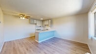 Located at 1600 N San Fernando Blvd in Burbank, CA, this two-bedroom, one-bathroom unit offers a practical and efficiently organized single-floor layout. The open-concept kitchen and living area serves as the heart of the unit, featuring a peninsula counter with a light-colored surface that doubles as a breakfast bar and room divider. The kitchen is equipped with a gas range, an undermount sink, and ample grey cabinetry providing generous storage. Light wood-style flooring runs throughout the main living areas, complemented by a ceiling fan with a light fixture overhead and a textured ceiling. Both bedrooms are carpeted and receive natural light through sliding windows with views of the surrounding building exterior. The primary bedroom includes a wall-mounted HVAC unit for individual climate control. A dedicated closet and hallway connect the living spaces to the full bathroom, which features a combined shower and bathtub, a single-sink vanity with storage drawers, and light wood flooring that maintains a clean, cohesive look throughout. The layout is straightforward and well-connected, making efficient use of the available space throughout the unit.