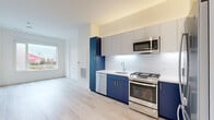 Located at 102 Mill Rd in Everett, Massachusetts, this thoughtfully designed one-bedroom, two-bathroom residence offers a efficient and modern living experience across a single floor. The open-concept layout seamlessly connects the kitchen and living area, maximizing the sense of space throughout.

The kitchen is a standout feature, showcasing bold navy blue lower cabinetry paired with light gray upper cabinets and gold-toned hardware. A white subway tile backsplash, stainless steel appliances — including a gas range, dishwasher, microwave, and refrigerator — and a clean white countertop complete the contemporary look. Light wood-style flooring runs throughout the main living areas, adding warmth and cohesion.

The bedroom is a comfortable, carpeted retreat featuring a large window that invites natural light and provides views of the surrounding neighborhood. The clean white walls and neutral tones create a calm, restful atmosphere.

The two bathrooms are finished in a clean, modern style, with large-format tile flooring, white subway tile surrounds in the tub/shower, and crisp white fixtures throughout.

Recessed lighting and large windows ensure the entire space remains bright and airy, while the clean, contemporary design provides a polished, move-in-ready environment in the heart of Everett.