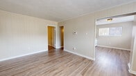 Located at 915 S College Rd in Lafayette, Louisiana, this one-bedroom, one-bathroom unit offers a practical and well-organized single-floor layout. Wood-look luxury vinyl flooring runs consistently throughout the space, providing a clean, cohesive aesthetic from room to room.

The living room features distinctive vertical shiplap-style wall paneling painted in a warm neutral tone, crown molding, and a wall-mounted thermostat for climate control. Multiple windows fitted with horizontal blinds allow natural light to fill the room, creating a bright and open feel. A six-panel front entry door with flanking windows reinforces the welcoming atmosphere.

The kitchen is efficiently designed with white upper and lower cabinetry, a single-basin sink with a matte black faucet, laminate countertops, and white appliances including a refrigerator and electric range with overhead ventilation.

The bedroom is a comfortable size, accented by a ceiling fan with integrated lighting, a window overlooking the exterior, and easy access to the hallway and closet. The neutral beige walls carry through from the rest of the unit, maintaining visual continuity.

The bathroom includes a tub/shower combo with a white surround, a window for natural ventilation, and wood-look flooring that matches the rest of the home. A dedicated closet and hallway complete this efficiently planned layout.