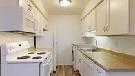 This 2-bedroom, 1-bathroom unit in Saginaw, Michigan offers a well-organized single-floor layout designed for comfortable everyday living. The galley-style kitchen is efficiently arranged with ample white cabinetry, light-toned countertops, wood-look vinyl flooring, and white appliances including a range, refrigerator, and over-the-range microwave. A notable convenience is the in-unit washer tucked neatly within the kitchen area. The open living area features plush carpet and flows naturally toward the front entry, with an open pass-through view into the kitchen. Large windows dressed with blinds allow natural light to brighten the living spaces. Both bedrooms are carpeted and generously sized, each with windows that bring in natural light. The primary bedroom includes a sliding-door closet offering practical storage space. The full bathroom features a white vanity with storage cabinetry, a large mirror, and wood-look vinyl flooring that ties in with the kitchen aesthetic. Throughout the unit, the neutral color palette of soft whites and warm beiges creates a clean, move-in-ready atmosphere that is easy to personalize.