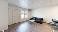 Located at 755 Burcham Dr in East Lansing, Michigan, this 2-bedroom, 1-bathroom unit offers a clean, functional layout across a single floor. The interior features consistent hardwood-style flooring and a neutral white color palette throughout, creating a cohesive and modern feel. The living room provides a comfortable open area with a front-facing window that lets in natural light, a wall-mounted TV setup, and a wall unit for climate control. The kitchen is well-appointed with white shaker cabinets, a classic subway tile backsplash, stainless steel appliances including a refrigerator, dishwasher, and range, as well as a peninsula for added counter space. Both bedrooms feature hardwood-style floors, white panel-style ceilings, and natural light from windows. The primary bedroom offers a generous footprint with mirrored sliding closet doors and built-in shelving, providing ample storage. The second bedroom is compact yet functional, with its own window and easy hallway access. The bathroom is clean and straightforward, featuring a full tub-shower combination, white fixtures, and a vanity. A connecting hallway ties the rooms together efficiently, maximizing the use of the compact floor plan.