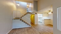 Located at 43524 Gadsden Ave in Lancaster, CA, this two-story home offers a well-designed layout across both floors. The main level immediately impresses with its dramatic double-height ceilings in the living area, creating an open, airy atmosphere. A carpeted staircase with white metal railings rises to the upper level, where an open loft-style overlook adds to the vertical scale of the space. A pendant light fixture accents the stairwell, enhancing the sense of height. Wood-look flooring runs throughout the main level, providing a cohesive and easy-to-maintain surface.

The kitchen is efficiently laid out and features cream-toned cabinetry with ample upper and lower storage, speckled laminate countertops, a gas range, dishwasher, and a skylight that introduces natural light. A narrow entry hallway leads to the main door, with a thermostat conveniently positioned nearby.

Upper-level rooms include generously sized bedrooms with vaulted ceilings, vertical blinds on windows that allow natural light, and ceiling fans for comfort. At least one bedroom includes a walk-in closet. Bathrooms feature speckled countertops with undermount sinks and large mirrors. A separate water closet provides added privacy. Throughout, textured ceilings and neutral tones create a clean, functional living environment.
