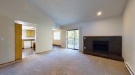 This single-floor residence offers a practical and functional layout across several well-defined living spaces. The living room serves as the focal point of the home, highlighted by a built-in fireplace with a dark surround and hearth, vaulted ceilings that lend a sense of openness, and a sliding glass door that opens onto a private balcony with outdoor views. Baseboard heating runs along the walls, and carpet flooring extends throughout the main living and bedroom areas.

The kitchen is equipped with oak cabinetry, a peninsula cooktop with additional counter space, a refrigerator, and a double sink with a window above. In-unit washer and dryer hookups are conveniently located just off the kitchen. Wood-look flooring carries through the kitchen and hallway areas.

The bedrooms are carpeted and each include sliding oak closet doors offering ample storage. One bedroom features a wall of closet space and direct access to a bathroom. The bathroom includes a single-basin vanity with dark countertops, dual mirrors, wood-look flooring, and an opening that leads to a walk-in closet area. A hallway connects the rooms and includes additional storage with a full-length door cabinet and coat hooks near the entry.
