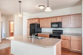 Located at 9220 Silverstone Ln in Verona, Wisconsin, this two-story home offers 2 bedrooms and 2 bathrooms across a well-planned layout. The main living level hosts an open-concept kitchen and living area bathed in natural light from multiple windows. The kitchen is outfitted with warm maple cabinetry, black appliances including a refrigerator, electric range, and built-in microwave, and a central island with a double sink and pendant lighting overhead. Hardwood-style flooring flows throughout the main living areas, complementing the bright, neutral color palette. The upper level features two carpeted bedrooms, each equipped with a ceiling fan and natural light from well-placed windows. The generously sized primary bedroom includes its own en-suite bathroom featuring a dual-sink vanity with ample cabinetry, tile flooring, and a separate water closet. The second full bathroom offers a single-sink vanity and a full tub-shower combination. Two closets provide convenient storage throughout the home. A utility room and hallway round out the interior spaces. The attached garage features an automatic opener, drywall-finished walls, a window, and a concrete floor, offering secure and practical parking or additional storage.