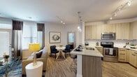This thoughtfully designed single-floor residence offers a seamless blend of modern aesthetics and functional living. The open-concept layout connects the kitchen, dining, and living areas into one cohesive, light-filled space. The kitchen is a standout feature, equipped with light wood cabinetry, quartz countertops, a stainless steel appliance suite including a French door refrigerator, electric range, and over-the-range microwave, and a peninsula with bar seating illuminated by elegant pendant lighting. Track lighting overhead adds a contemporary touch. The living area is anchored by a gray accent wall adorned with decorative wall art, and large windows allow generous natural light while offering a view to the outdoors. Wood-look flooring flows throughout the main living areas, adding warmth and continuity. The primary bedroom features a bold navy accent wall, plush carpeting, and ample natural light from large windows with decorative drapery. A second bedroom is equally well-lit and comfortable, with soft carpet and bright windows. The bathroom includes tile flooring, a granite-topped vanity, a walk-in shower with frosted glass, and direct access to the adjacent bedroom. The overall ambiance is modern, refined, and welcoming throughout.