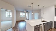 Located in Scottsdale, AZ, this well-designed two-bedroom, two-bathroom residence offers a thoughtfully planned single-level layout with modern finishes throughout. The open-concept living and kitchen area serves as the heart of the home, featuring warm wood-look flooring, recessed lighting, and a ceiling fan. The kitchen is a standout, showcasing gray shaker-style cabinetry, white quartz countertops, a large center island with pendant lighting, stainless steel appliances, and a tile backsplash — ideal for both everyday cooking and entertaining. The living area extends toward a sliding glass door that brings in natural light and outdoor access. Both bedrooms are carpeted and equipped with ceiling fans and windows. The primary bedroom includes a spacious walk-in closet with built-in shelving, accessible through a stylish black-hardware barn door. Each bathroom is finished with gray vanity cabinetry, dual sinks, white quartz countertops, and wood-look flooring. The primary bath features a glass-enclosed walk-in shower, while the second bath includes a tub-shower combo. Two walk-in closets provide generous storage throughout the residence.