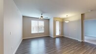 This well-appointed single-floor residence offers a thoughtfully designed layout that balances open living spaces with private quarters. An entry hallway with wood-look flooring welcomes you into the home, leading to a spacious open-concept living and dining area. The living space features ceiling fan lighting, neutral-toned walls, and large windows fitted with blinds that invite natural light while maintaining privacy.

The kitchen is a standout feature, showcasing dark espresso cabinetry, granite countertops, a white subway tile backsplash, and a full suite of stainless steel appliances including a refrigerator, range, microwave, and dishwasher. A central island with pendant lighting serves as both a prep area and gathering point. A convenient built-in desk nook adds functional workspace just off the kitchen.

The primary bedroom is generously sized with plush carpeting, a ceiling fan, and access to a private en-suite bathroom. The en-suite features dark vanity cabinetry, white quartz countertops, tile flooring, and a glass-enclosed walk-in shower. A second bedroom, also carpeted with a ceiling fan and ample natural light, is served by a full hallway bathroom complete with a soaking tub, tiled surround, and dark vanity with quartz countertop. Double closet doors provide generous storage throughout.