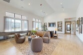 Located at 10203 Karsten Blvd in Rosharon, TX, the Broadstone at Sierra Vista clubhouse is a thoughtfully designed, single-story amenity facility spanning a generous footprint. The space greets visitors through a bright, glass-paneled entry foyer featuring a striking geometric accent wall, light wood-look flooring, and comfortable seating — setting a welcoming, upscale tone from the moment of arrival.

The main lounge area impresses with soaring vaulted ceilings and expansive windows that flood the interior with natural light. Built-in shelving, a wall-mounted TV, and curated furnishings with warm, neutral tones create an inviting gathering space. A connecting hallway links the lounge to additional areas, with framed artwork adorning the walls throughout.

A secondary lounge or flex room offers a more intimate setting, featuring patterned area rugs, plush seating, and sheer-draped windows with views to the outdoors. This space opens via glass-paneled doors, maintaining visual connectivity with the rest of the facility.

The fitness center is a standout feature, offering a well-equipped workout space with high ceilings, a tray ceiling detail, ceiling fans, large mirrors, and an array of strength and cardio equipment. Dumbbell racks and cable machines are positioned throughout the carpeted floor, while natural light pours in through large windows. The leasing or reception area rounds out the facility with pendant lighting and a clean, modern aesthetic.