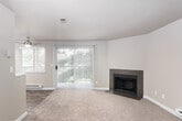 This single-floor residence offers a thoughtfully laid-out interior with a mix of carpet and hardwood-style flooring throughout. The spacious living room is a standout feature, centered around a tile-surround fireplace and bathed in natural light from large sliding glass doors that open to a private balcony overlooking lush greenery. A textured ceiling and baseboard heating add to the room's functional character.

The open-concept layout connects the living area to a well-appointed kitchen, which features rich dark-espresso cabinetry, white countertops, stainless steel appliances including a freestanding range, and a ceiling fan overhead. A window above the sink allows natural light to fill the space. The kitchen flows seamlessly into the dining and living areas, making it ideal for everyday living.

The bedrooms are carpeted and generously sized, each offering neutral tones and sliding closets with built-in hanging rods for ample storage. The bathroom includes a full-size soaking tub and shower combination with clean white surround walls and wood-style flooring. Throughout the residence, neutral warm-toned walls, white trim, and consistent finishes create a cohesive and inviting atmosphere.